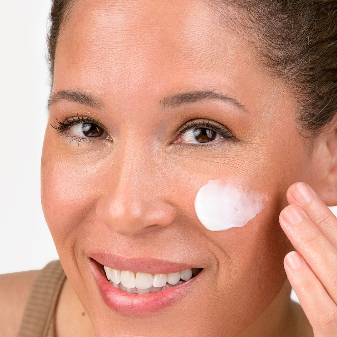 Woman applying Bio-Therapeutic Shade SPF 30 Climate Control sunscreen to cheek for sun and pollution protection